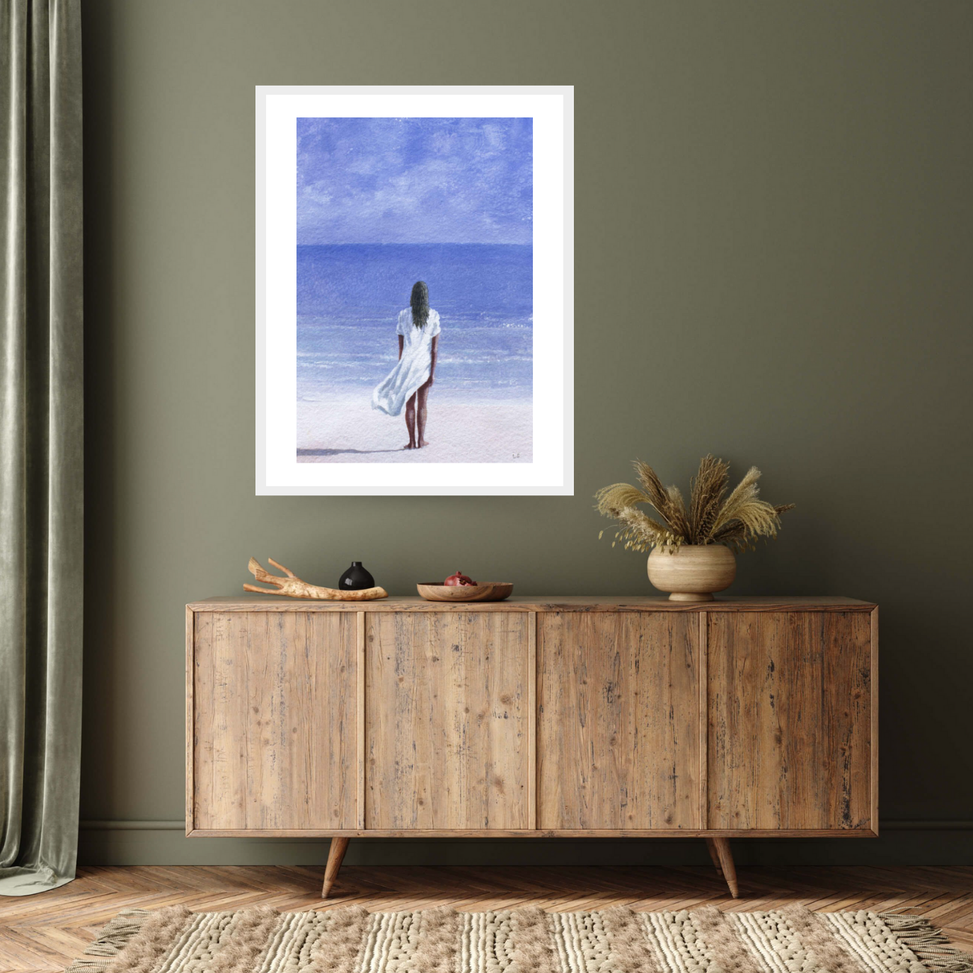 "Girl on Beach, 1995" by Lincoln Seligman. This captivating white framed print depicts a woman in a flowing white dress standing on the pristine sands, gazing towards the azure waters. Bring the tranquillity of the seaside into your space with this archival digital print on Hahnemühle German etching paper.