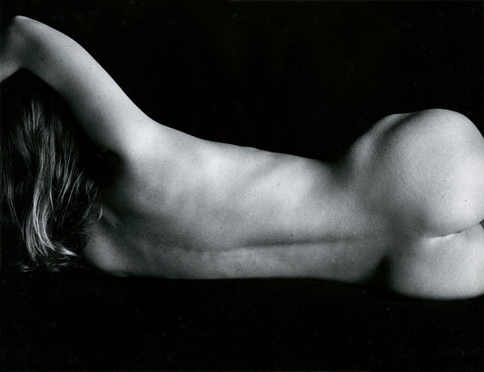 8389936An unframed black and white print titled ‘Classic Nude’ by Brett Weston that capture an elegant rear-facing nude female figure reclining on their side